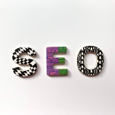 A whiteboard displaying three large SEO letters in different colors.