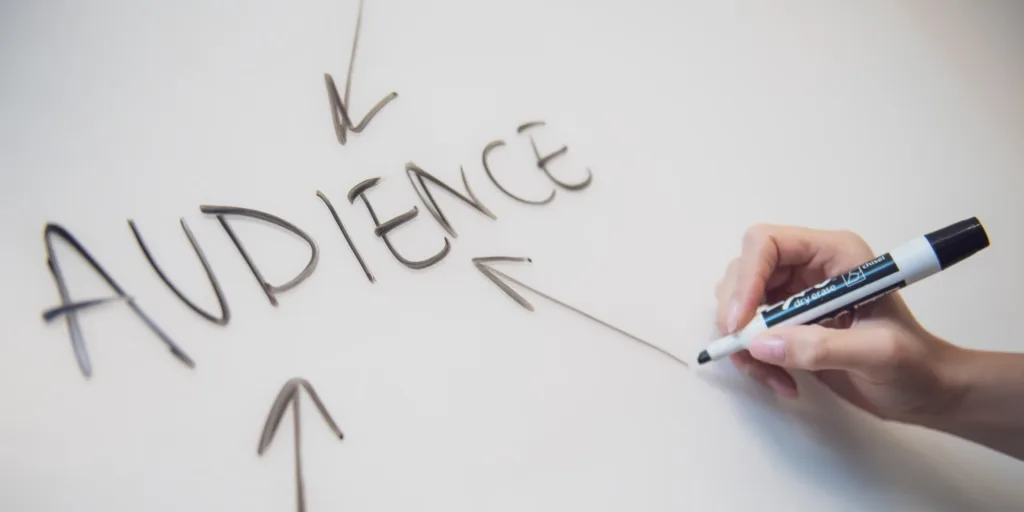 What is an audience, and how to create one? An image of a whiteboard with a handwritten sign that reads 'Audience' in capital letters, underlined for emphasis. The sign is surrounded by a blank space, suggesting the possibility of brainstorming or note-taking.