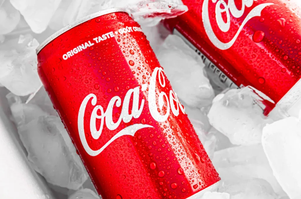 Chilled Coca-Cola cans resting on a bed of ice.