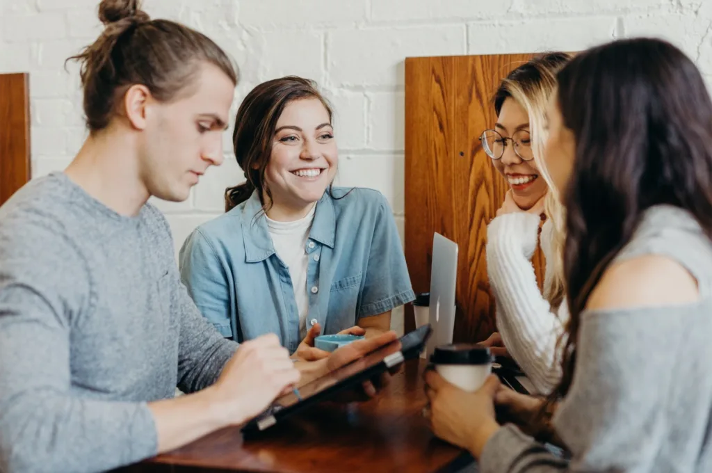 A group of individuals engaged in lively conversations, gathered closely in a relaxed setting. They are sharing experiences, opinions, and recommendations with enthusiastic gestures, embodying the essence of word-of-mouth advertising. The genuine interactions reflect the power of personal recommendations and their impact on spreading information organically.