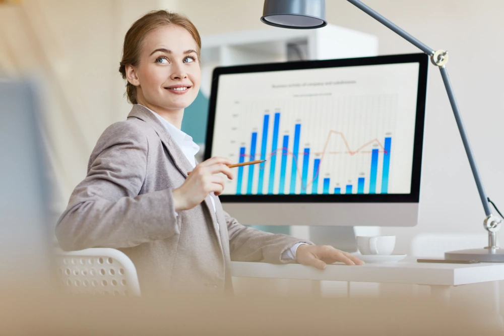 A professional woman presenting data analytics on a computer screen.